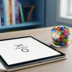 Close-up of a homeschool math desk with a notebook and tablet showing a simple math symbol area, plus colored counting pieces under soft natural light.